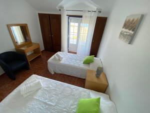 a bedroom with two beds and a chair and a mirror at Ericeira Sand Beach R6 in Ericeira