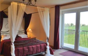 a bedroom with a canopy bed and a sliding glass door at 4 Bedroom Awesome Home In Saint-pierre-sur-orth in Sillé-le-Guillaume