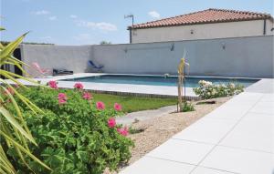 a swimming pool in a yard with pink flowers at Stunning Home In Sernhac With Swimming Pool in Sernhac