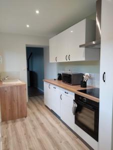 a kitchen with white cabinets and a sink and a microwave at Gite le Biardais in Balleroy