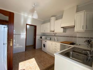eine Küche mit weißen Schränken und einer Spüle in der Unterkunft Ericeira Sand Beach RCT in Ericeira