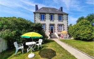 a table with an umbrella in front of a house at Awesome Home In Morlaix With 3 Bedrooms in Sainte-Geneviève