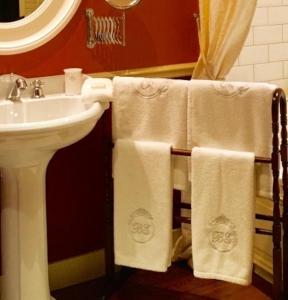 a bathroom with a sink and white towels at Brugsche Suites - Luxury Guesthouse in Bruges