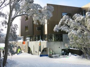 a building with snow on the ground in front of it at Buller Central Hotel in Mount Buller