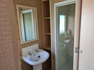 a bathroom with a sink and a shower and a mirror at 10 Berth on The Chase (Torbay) in Ingoldmells