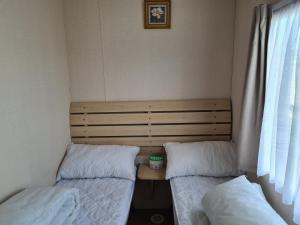a room with two beds and a table and a window at 10 Berth on The Chase (Torbay) in Ingoldmells
