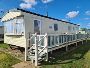 a mobile home with a porch and a deck at 10 Berth on The Chase (Torbay) in Ingoldmells