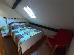 1 dormitorio con 1 cama y 1 silla roja en Gîte * Gaïa *, en Châtel-Montagne