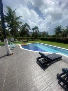 uma piscina com um banco ao lado de um resort em Casa Branca do Paiva em Cabo de Santo Agostinho