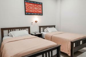 twee bedden naast elkaar in een kamer bij Pasola Guest House in Medan