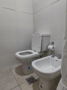 a white bathroom with a toilet and a sink at Cabrera in Junín