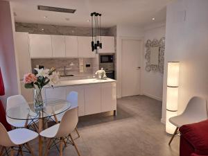 a kitchen and dining room with a glass table and white cabinets at LEVANTE SUITES in Benidorm