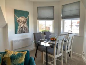 ein Esszimmer mit einem Tisch und einem Kuhgemälde an der Wand in der Unterkunft Luxurious Loft Flat 2-bed/2-bath in South Shields