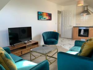 salon z 2 niebieskimi krzesłami i telewizorem z płaskim ekranem w obiekcie Luxurious Loft Flat 2-bed/2-bath w mieście South Shields
