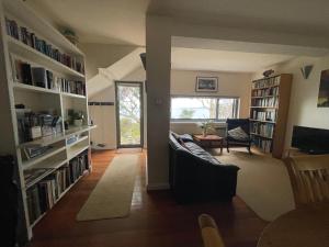 a living room with a couch and bookshelves at Beachside Taroona with Spa in Sandy Bay