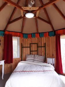 a bedroom in a log cabin with a bed in it at LA HUTTE MASSAÏ in Villelaure