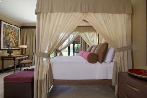 a bedroom with a canopy bed and a desk at Villa Senja in Tanah Lot