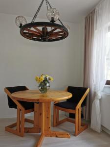 a wooden table with two chairs and a vase of flowers at La Casa Suciu in Forchtenberg