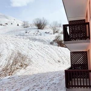 a snow covered hill with a building and a balcony at Valmeinier in Valmeinier
