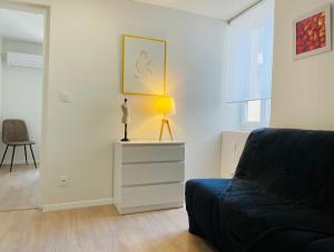 a living room with a couch and a lamp on a dresser at Hotel De Ma Tante in Lamalou-les-Bains