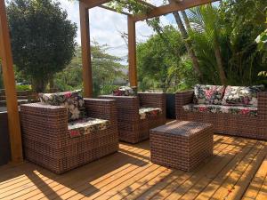 un groupe de chaises et de tables en osier sur une terrasse en bois dans l'établissement Suítes Jurerê Internacional, à Florianópolis