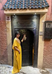 une femme debout devant une porte dans l'établissement Dar princesse jamila, à Marrakech