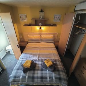 a bed in a small room with two towels on it at 2-Bed Caravan at Billing Aquadrome Northampton in Northampton