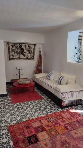 Sala de estar con 2 camas y mesa en Maison d'hotes Berbari, en Asilah