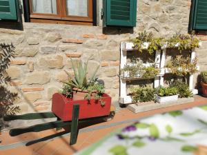 um carrinho vermelho cheio de vasos de plantas em frente a um edifício em Casa Velia em Uzzano