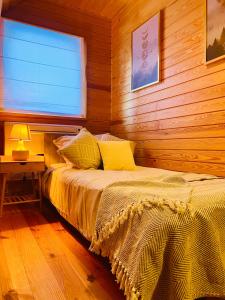 a bed in a wooden room with a window at Przystanek Tonkiele in Tonkiele