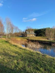 a house in a field next to a river at Przystanek Tonkiele in Tonkiele