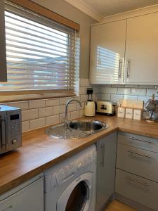 een keuken met een wastafel en een wasmachine bij Modern 2 Bed Chalet - 27 Bermuda Holiday Park in Hemsby