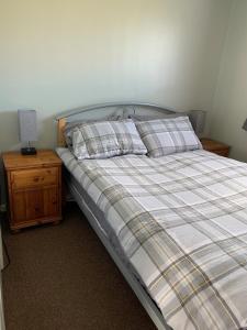 a bed with a plaid blanket and pillows on it at Modern 2 Bed Chalet - 27 Bermuda Holiday Park in Hemsby