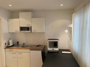 eine kleine Küche mit weißen Schränken und einer Mikrowelle in der Unterkunft City Apartments in Bad Säckingen