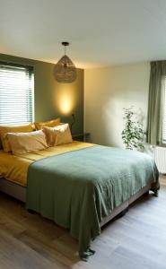 um quarto com uma cama grande e um cobertor verde em Bed and Breakfast het Groentje em Staphorst