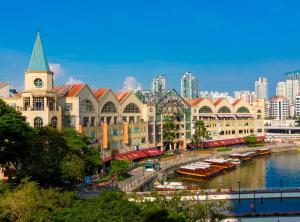 a building with a clock tower next to a river at Paradox Singapore Merchant Court at Clarke Quay in Singapore