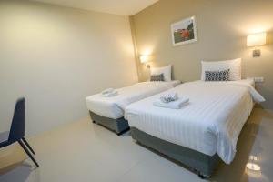 una habitación de hotel con 2 camas y una silla en Sleepstation at Pratunam, en Bangkok
