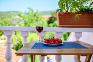 a glass of wine and a plate of fruit on a porch at Apartmani Noris (app3) in Martinšćica