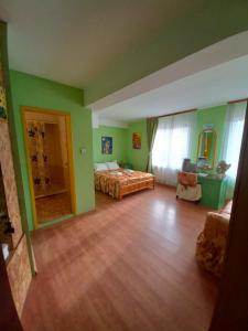 a bedroom with a bed and green walls and wooden floors at Hadjibulevata Guest House in Kovachevtsi