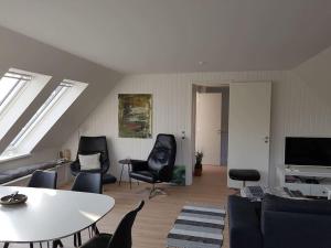 Havudsigt Ferielejlighed في Dannemare: غرفة معيشة مع كراسي سوداء وطاولة
