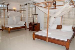 two beds in a room with white floors and windows at SULKHAN SERVICED APARTMENT in Chukwani