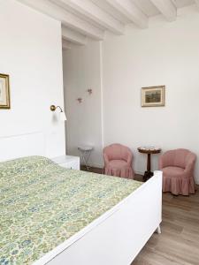 1 dormitorio blanco con 1 cama y 2 sillas rosas en "La Cascina" Bed & Breakfast, en Desenzano del Garda