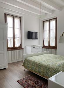 1 dormitorio blanco con 1 cama y TV en "La Cascina" Bed & Breakfast, en Desenzano del Garda