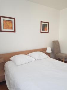een slaapkamer met een wit bed en een stoel bij L'Appart Vue Mer in La Rochelle