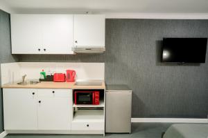 una cucina con armadi bianchi e forno a microonde rosso di Mavie Apartment Boutique a Bucarest