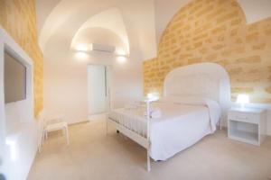 een witte slaapkamer met een bed en een stoel bij Antiche Dimore in Mazara del Vallo
