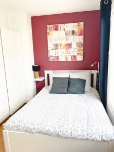 um quarto com uma cama branca e uma parede vermelha em Appartement A Deux Pas situé en Hyper Centre Ville em Rouen