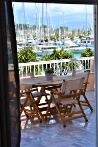 a wooden table and chairs on a balcony with boats at Christina's apartment in Kontokali