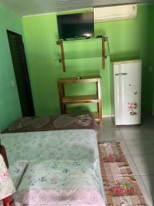 Grünes Zimmer mit einem Bett und einem Kühlschrank. in der Unterkunft Estância Cyclo das Águas in Nobres