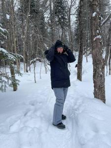 a person standing in the snow near a tree at Chalet le Huard directement au bord du lac in Saint Zenon